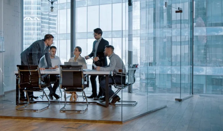 Réunion de négociation commerciale B2B dans la salle vitrée d'un immeuble de bureaux